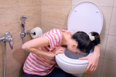 女人一个年轻女子在马桶里呕吐的特写一个年轻女子在马桶呕吐时显示