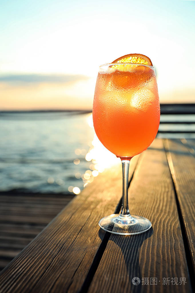 日落时在户外的木桌上放一杯新鲜的夏日鸡尾酒