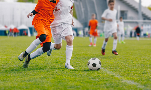 初级男孩在草地上踢足球比赛.青少年足球赛.儿童体育比赛.