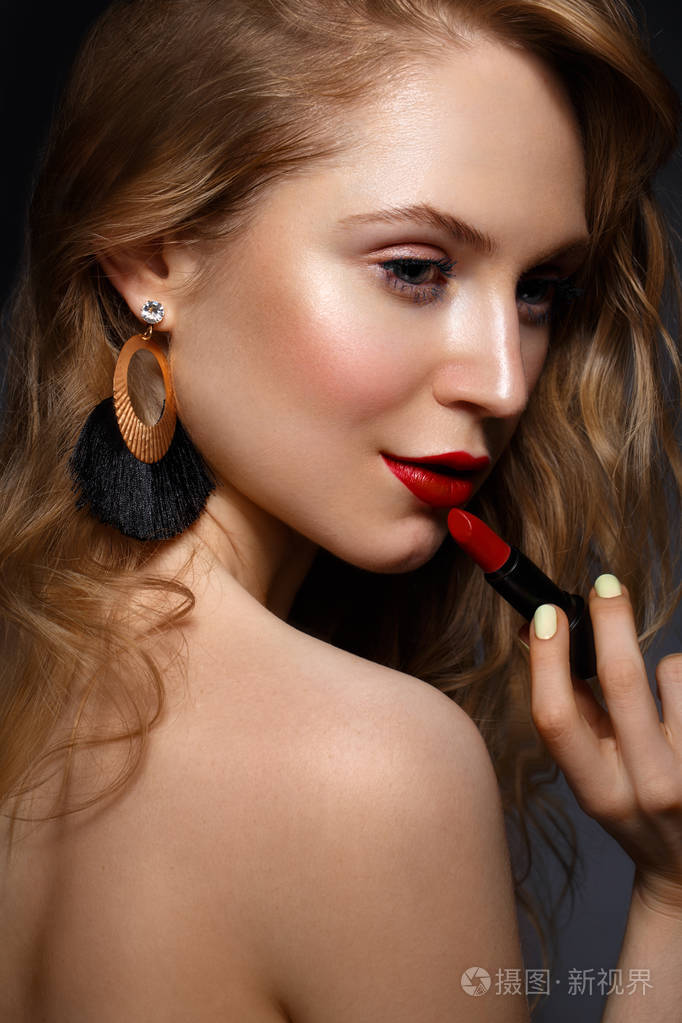 美丽的女孩红嘴唇和经典化妆和卷发与唇膏在手美丽的脸庞