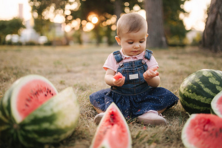 可爱的小女孩笑着吃西瓜.穿牛仔裙的女孩.夏季户外儿童和西瓜肖像.