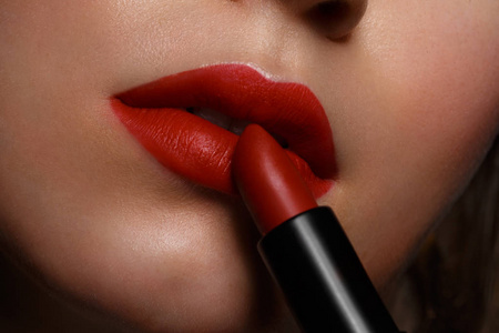 美丽的女孩红嘴唇和经典化妆和卷发与唇膏在手.美丽的脸庞照片