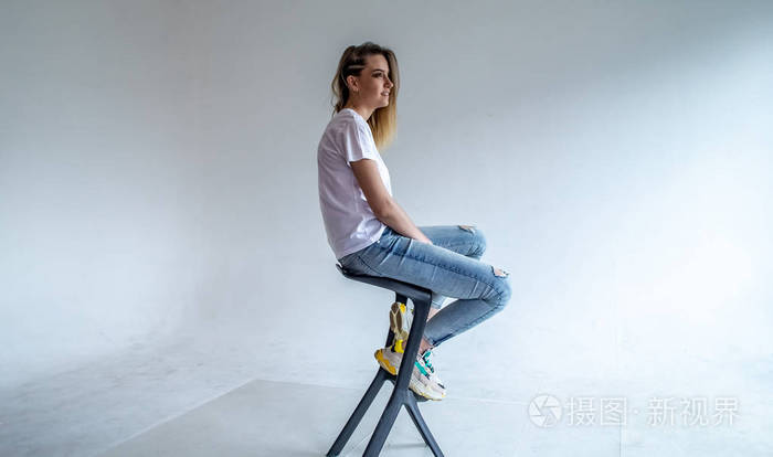 穿着白色t恤坐在酒吧椅子上的女孩