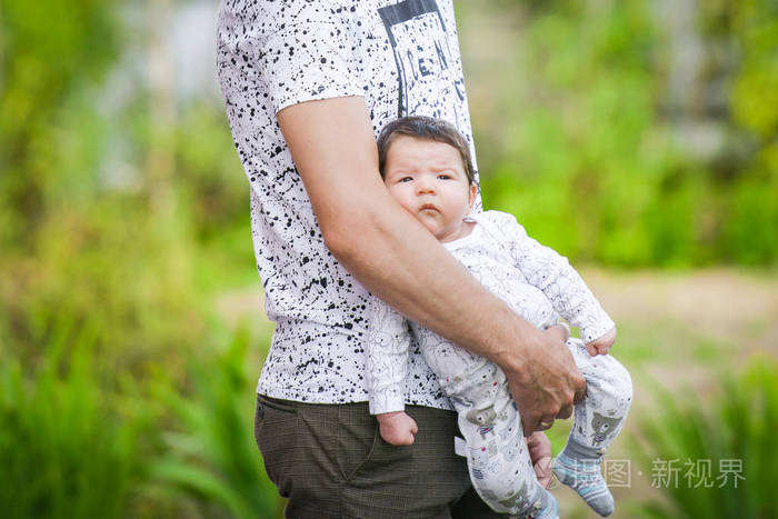 新生儿在男性怀抱中睡觉的特写肖像.年轻快乐的爸爸抱着孩子微笑.