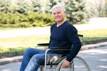 阳光明媚的一天,坐轮椅的老人在公园里照片