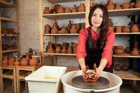 美丽的陶艺女孩在马斯特用陶罐做模具.一个女人用陶土在陶土轮上工作.