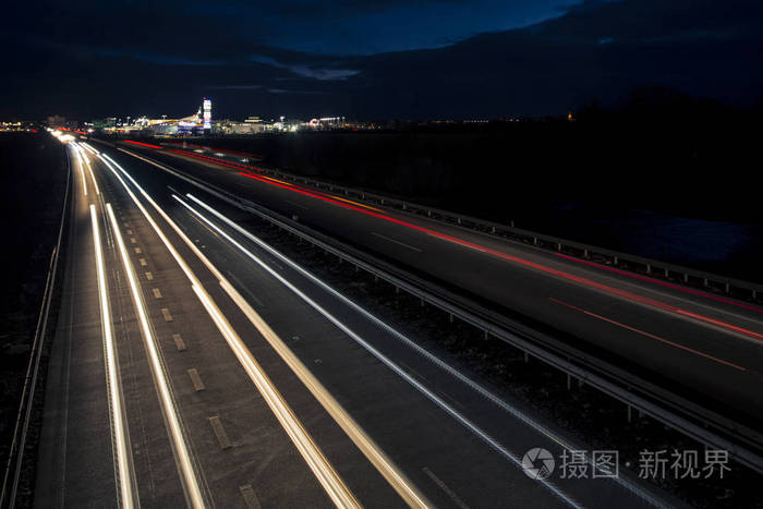 夕阳西下后，运动模糊的灯光轨迹在通往城市的公路交通的黑暗中闪闪发光。