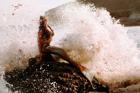 白种红发女子与美人鱼尾栖息在岩石上与p照片