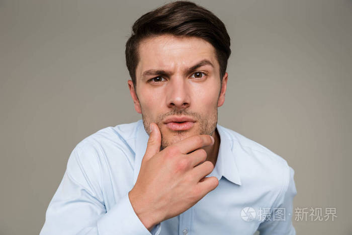 图片特写镜头是一个严肃认真的男人穿着正装看着镜头抚摸着下巴