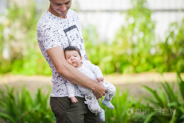 他父亲怀里的新生婴儿一位父亲抱着刚出生的婴儿快乐的父亲