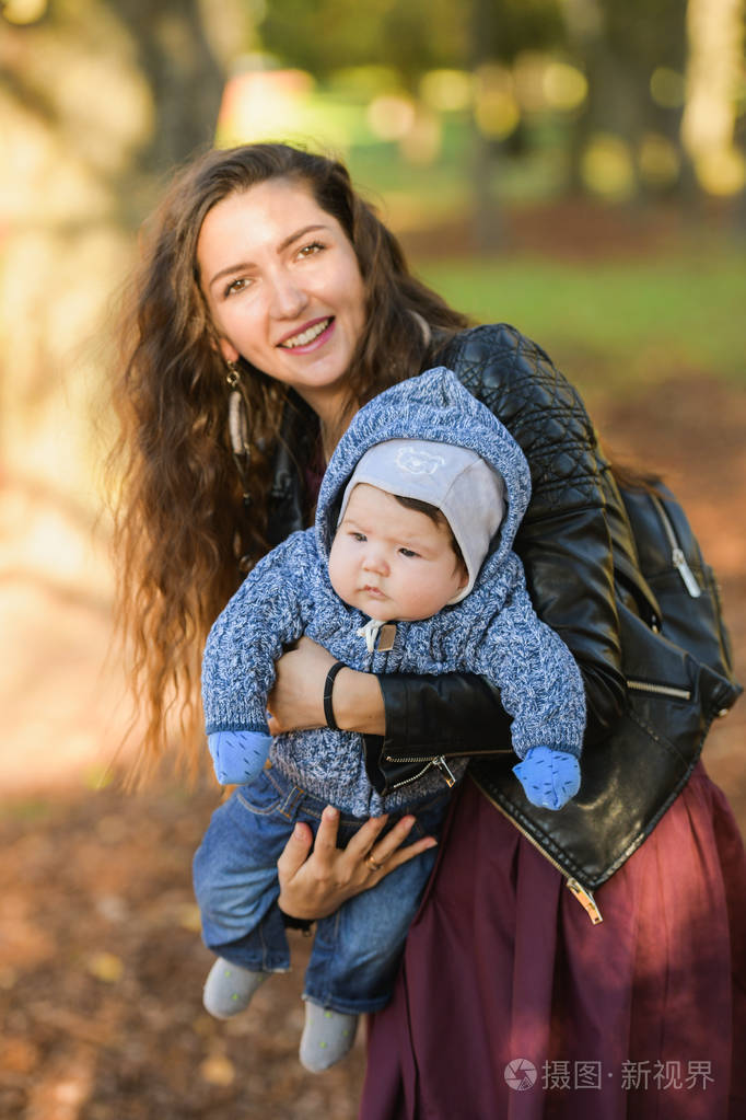 妈妈怀里的宝宝很有趣.年轻漂亮的母亲抱着儿子.