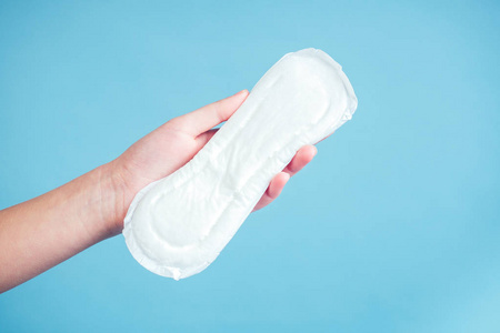 卫生巾背景女孩手上的白色卫生巾,背景是蓝色照片