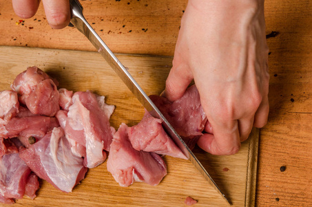 女性手拿刀在桌子上切新鲜的肉图片