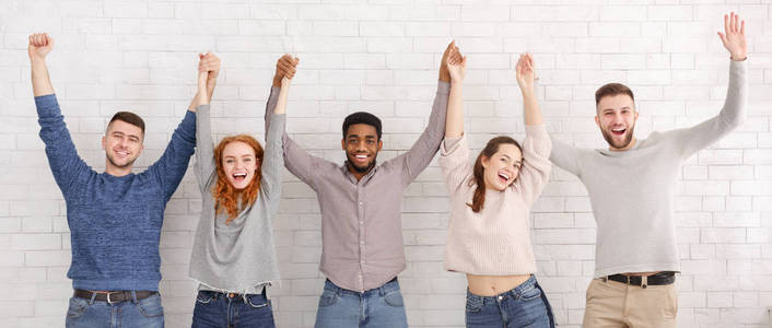 高举双手朋友们高举双手高举在白墙上庆祝成功照片