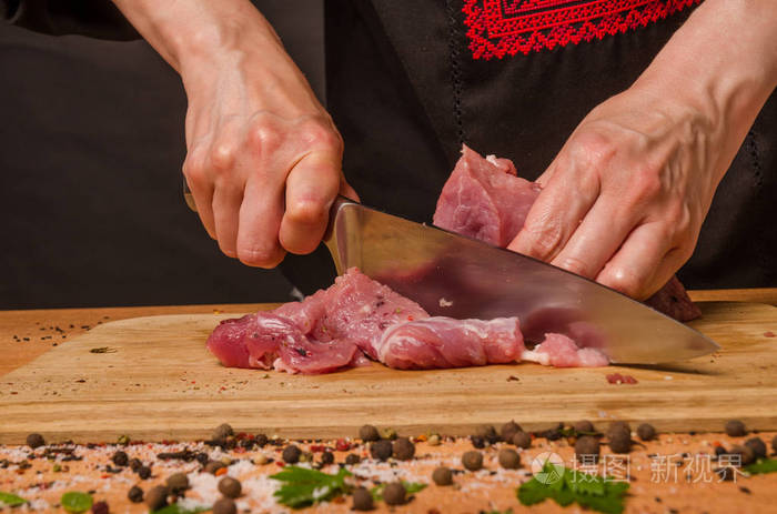 女性手拿刀在桌子上切新鲜的肉