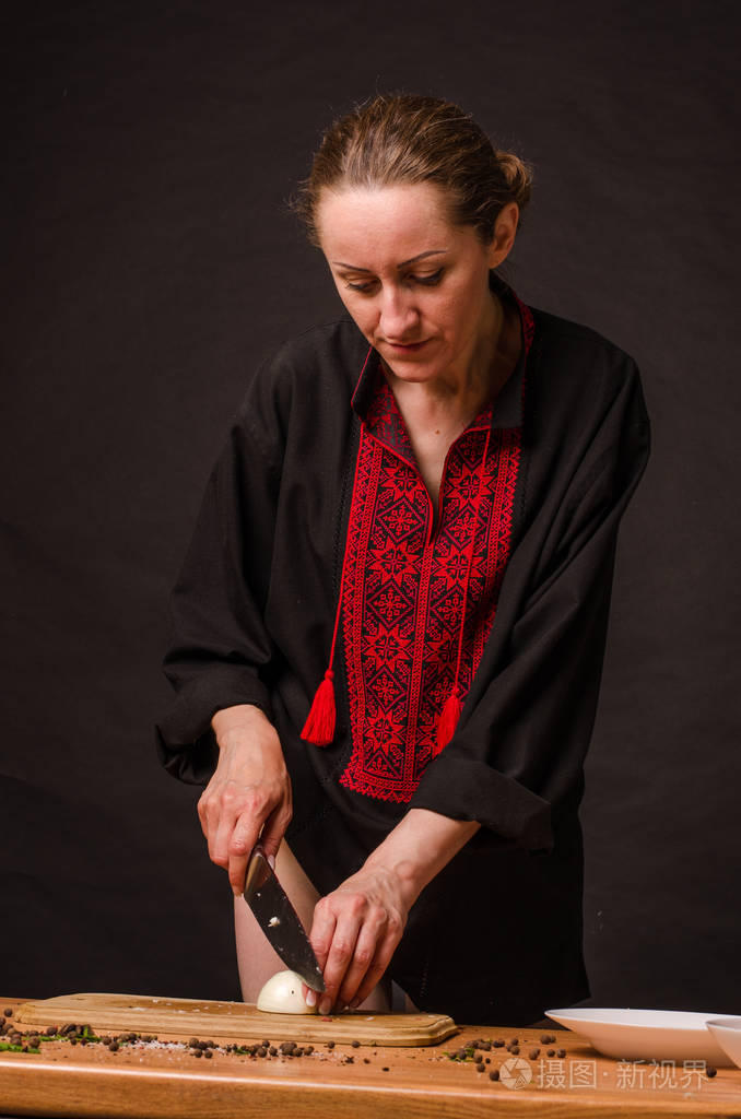 女孩的手拿着刀在木板上切洋葱