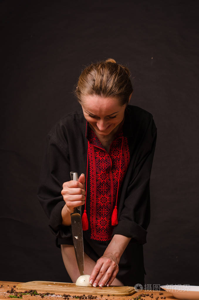 女孩的手拿着刀在木板上切洋葱