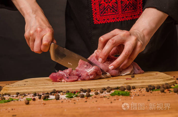 女性手拿刀在桌子上切新鲜的肉