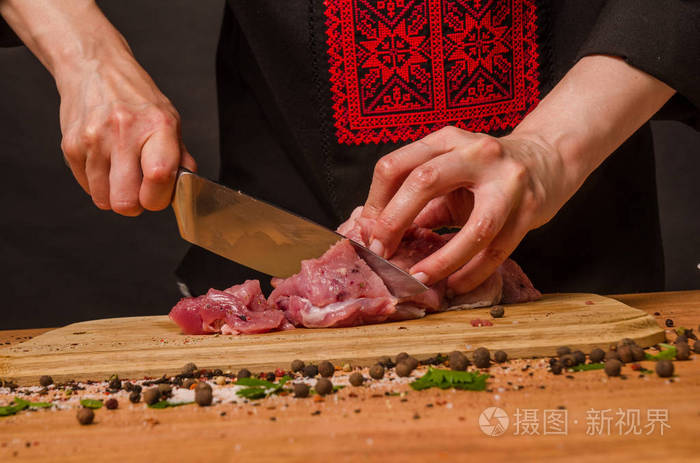 女性手拿刀在桌子上切新鲜的肉
