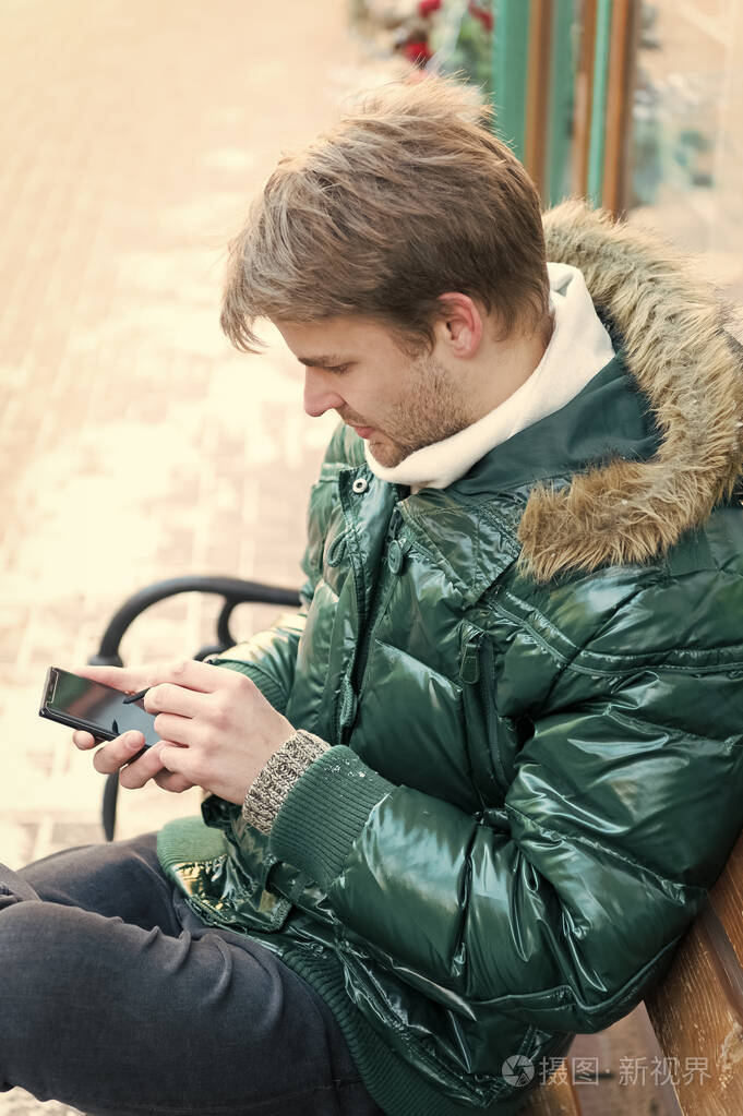 时髦的人在冬天用智能手机.帅哥拿着智能手机.