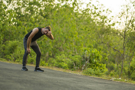 汗流浃背,疲惫不堪的男子在美丽的乡村道路上进行户外跑步锻炼,呼吸