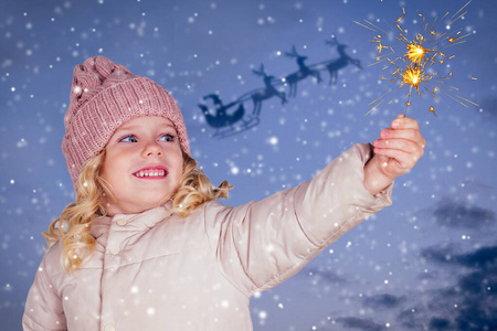 雪天老人戴着针织帽子的小女孩拿着深蓝色的烟花背景.