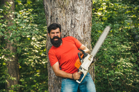 一脸严肃的伐木工人拿着电锯.锯木厂里带着链锯的伐木工人.照片