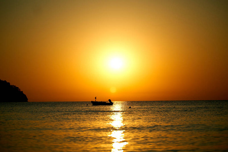 橘黄色的夕阳在海面上与船惊人的金色反射太阳平静的波浪照片