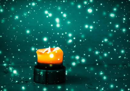 在品牌上的星星橙色假日蜡烛在绿色闪耀的雪景背景上,勒克斯照片