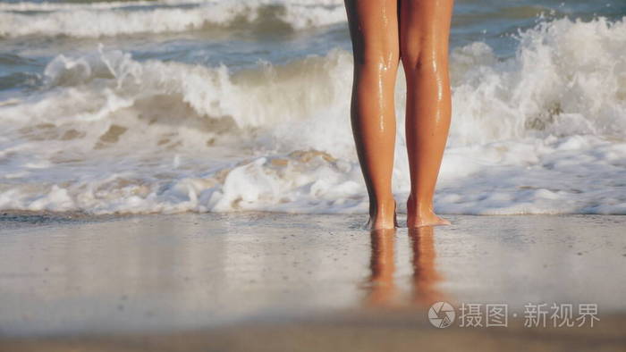 女孩被海浪洗脚，特写