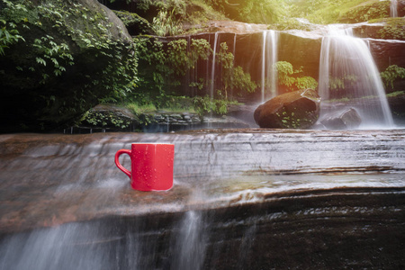 瀑布自然背景的红色咖啡杯图片