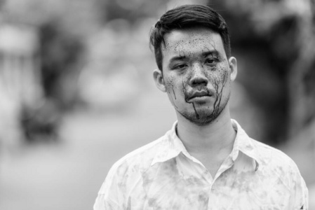 年轻疯狂的亚洲人在户外满脸是血照片