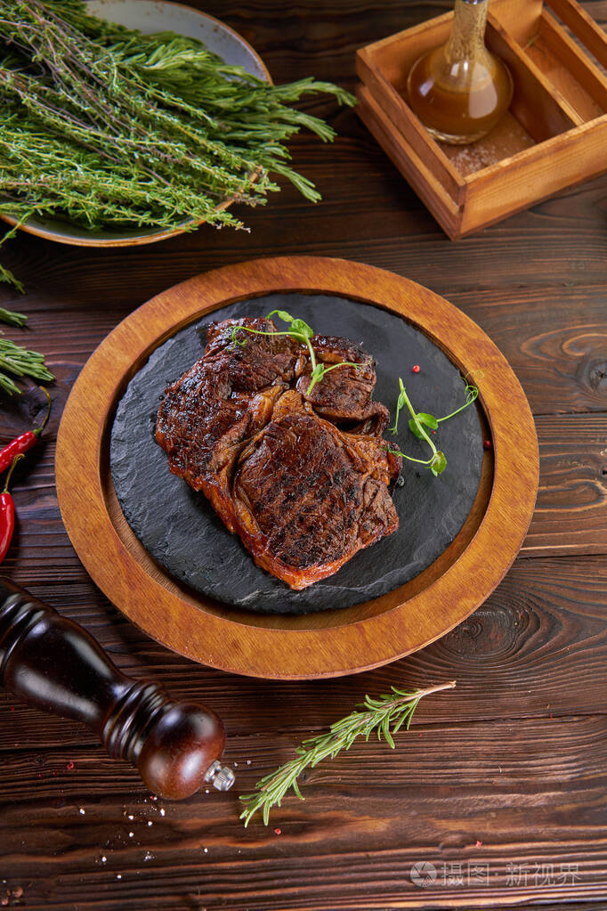 老桌子上的圆形木制托盘烤牛排俯视图