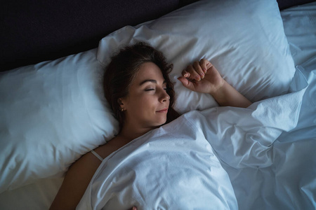 独自睡觉年轻漂亮的女孩或女人独自睡在大床上,近距离俯视照片