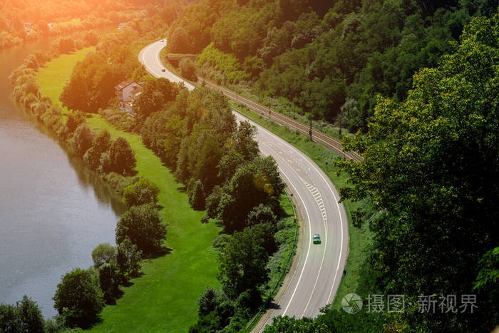 一条风景如画的蜿蜒公路沿着河岸延伸,紧挨着铁轨,在壮丽的大自然背景