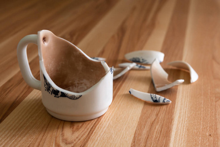 木质背景上有碎片的碎白色杯子照片