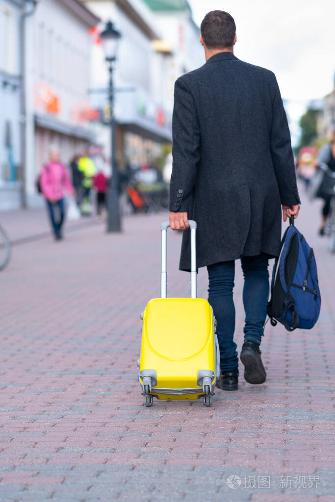 一个男人拉着一个黄色的手提箱走了
