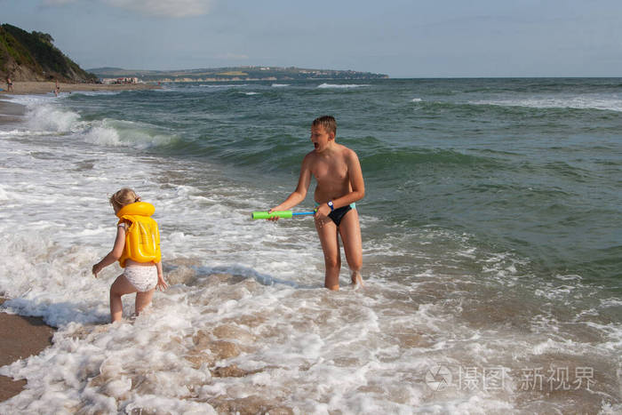 两个孩子一个男孩和一个女孩，一个哥哥和一个妹妹正在海边的水里玩耍。