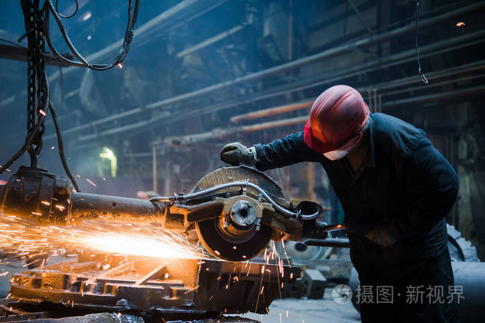 用大型电动磨床切割金属在工厂与钢材工作时橙色火花飞溅危险作业概念
