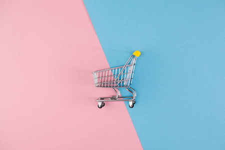 一个独立的手推车和购物篮在粉红色和蓝色的背景上一分为二.复制空间.