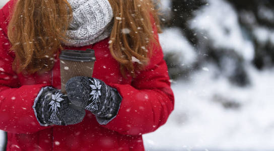 雪地上拿着热饮料的纸杯的女人图片