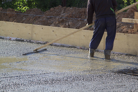 的水泥里,用一个特殊的木制工具将底板(新浇混凝土板)的表面找平照片