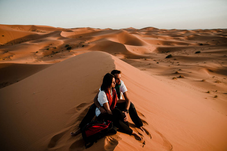 一对夫妇坐在撒哈拉沙漠的沙丘上照片