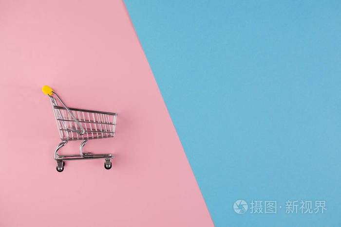 特写.一个独立的手推车和购物篮在粉红色和蓝色的背景上一分为二.