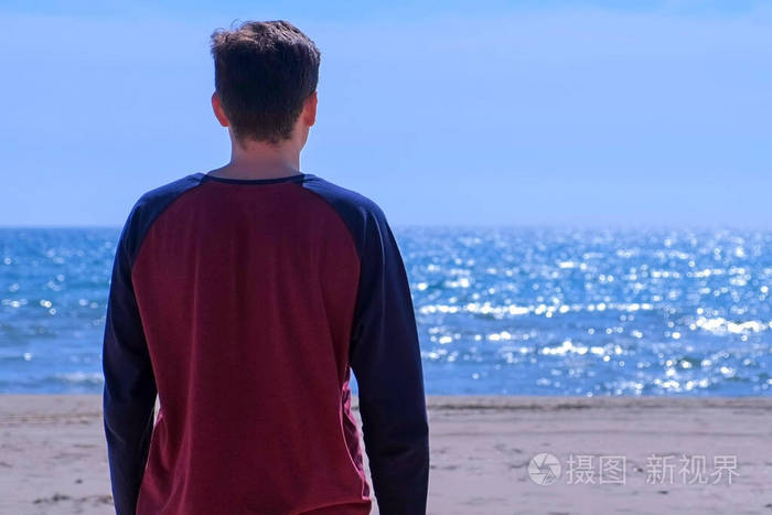 年轻人正在沙滩上看海背影