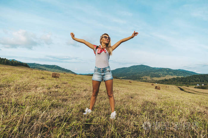举起双手脸上流露出喜悦的情绪一个年轻的女人在夏日的田野里伸展身体
