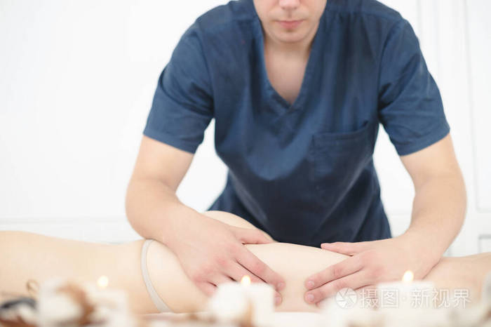 一个男按摩师的手臂特写为一个女孩做臀部按摩在温泉沙龙按摩与身体
