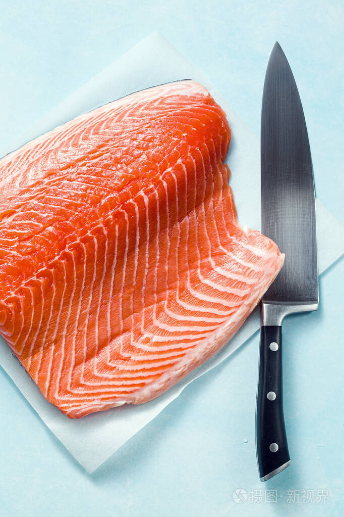 新鲜的三文鱼切片在一个木制的砧板上用厨师的刀