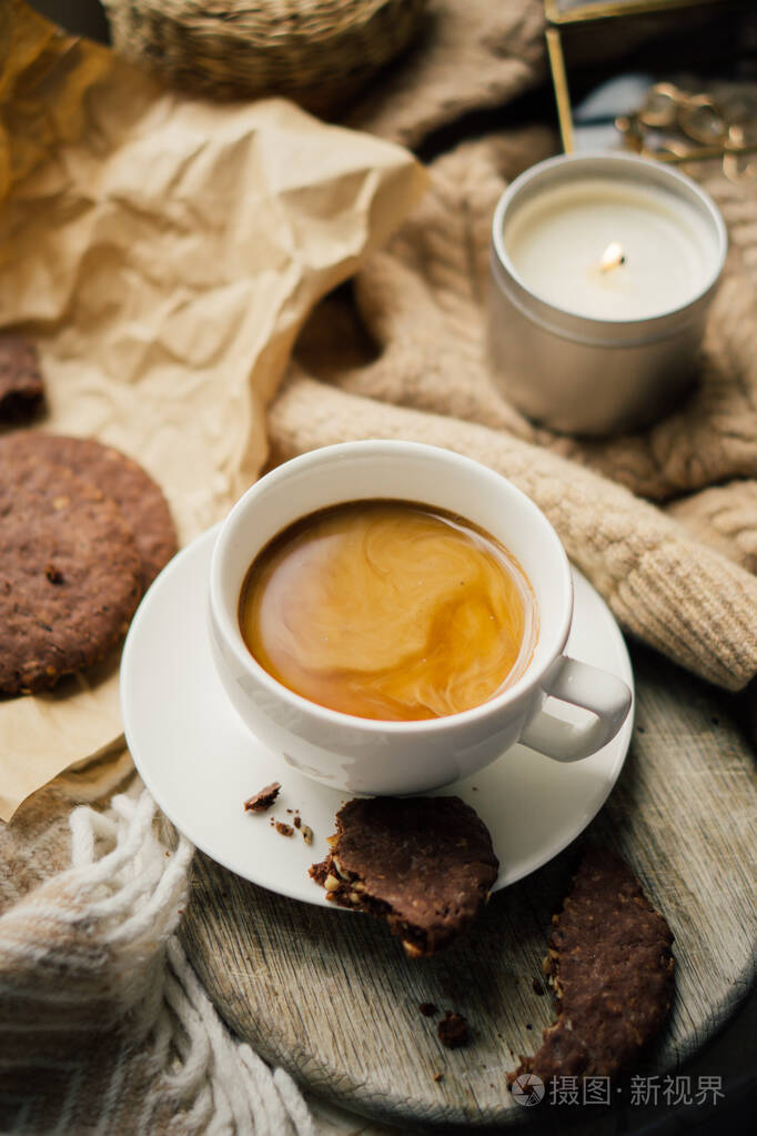 一杯加牛奶和巧克力曲奇的咖啡放在温暖的羊毛毯上