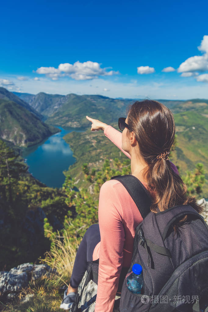 站在山顶上展现美丽自然的年轻女性旅行者